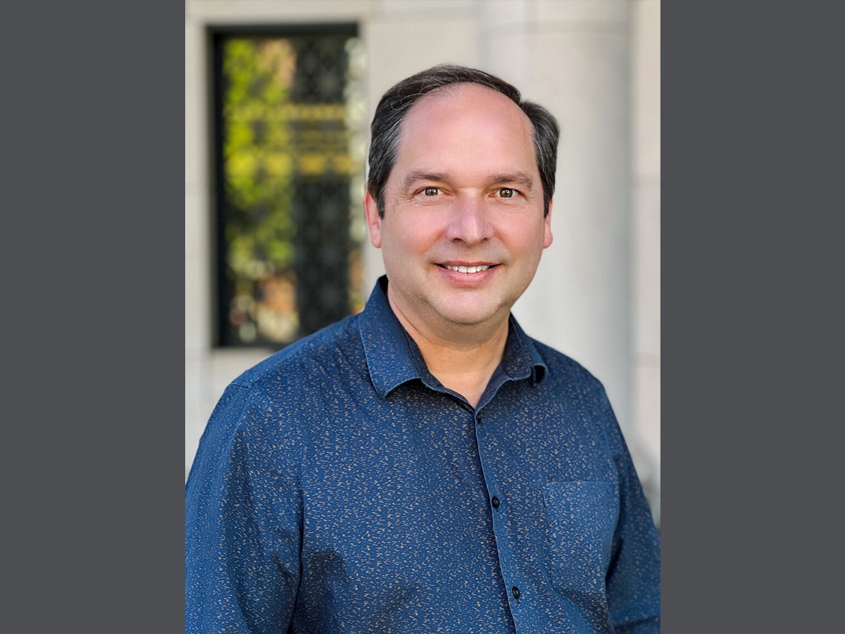 Headshot of Lawrence Sincich, Ph.D., wearing a blue shirt and sitting in front of a window.