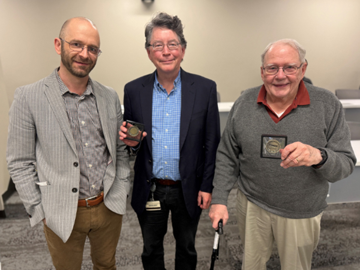 Wink Crittenden, Ph.D. (left), licensing associate at the Bill L. Harbert Institute for Innovation and Entrepreneurship, presents a Patent Coin to Tim Gawne, Ph.D. (center), professor, and Thomas Norton, Ph.D. (right), professor emeritus in the School of Optometry, recognizing their newly patented lens design aimed at slowing myopia progression in children.