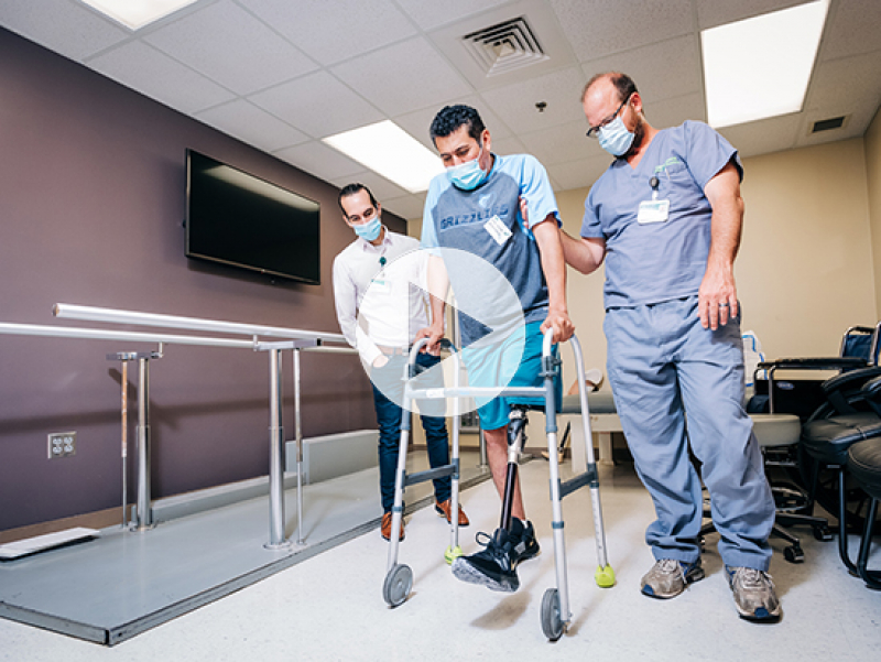 Brian Mueller, certified prosthetist and manager of the UAB Orthotics and Prosthetics Clinic, assists Hernandez in his first steps since the accident. (Photo by: Andrea Mabry)