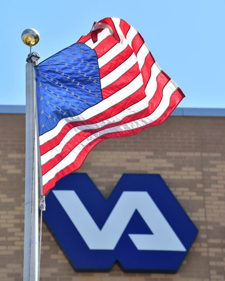 United States flag flying outside VA building with the VA logo in the background