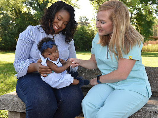 Mother holding child outdoors durring an a Nurse Family Partnership visit