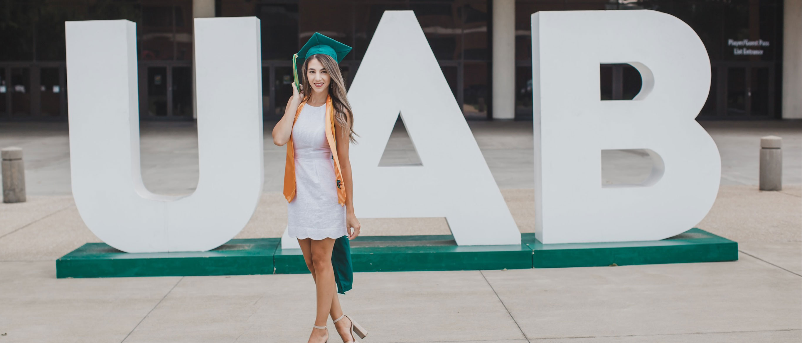 Christy posing in graduation cap in front of UAB lettering.