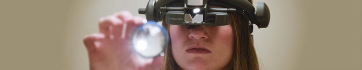 UAB Optometry student wearing aparatus examining a lense.
