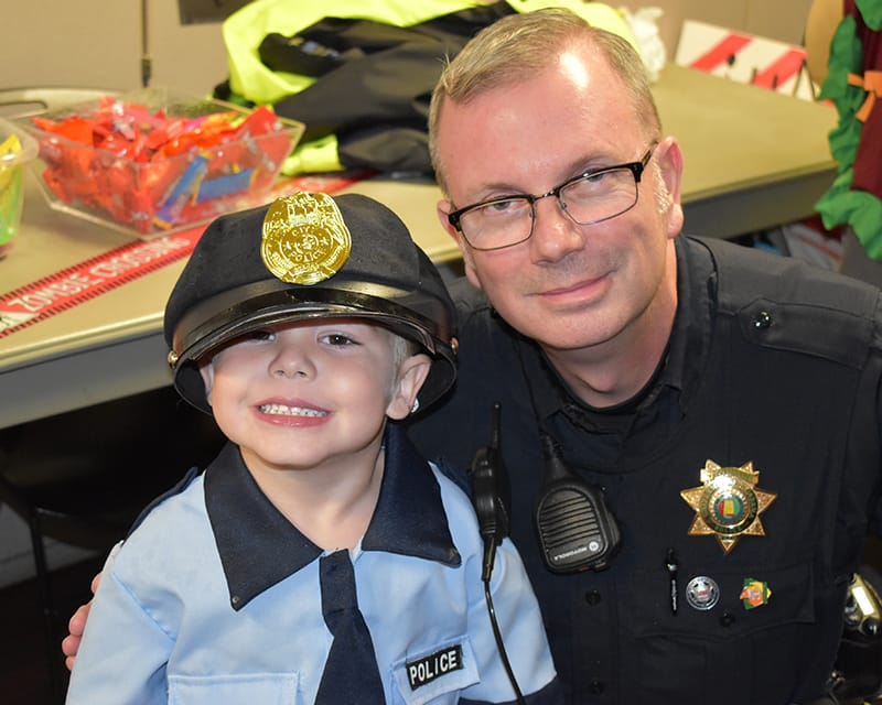 Police Officer posing with a young boy in his Police costume
