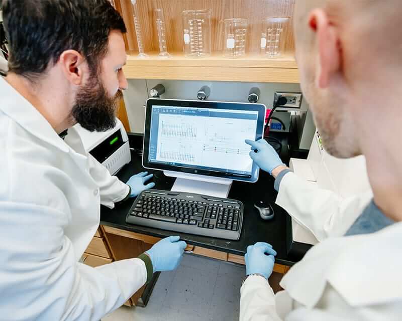 Two postodcs reading a computer screen in a lab. 