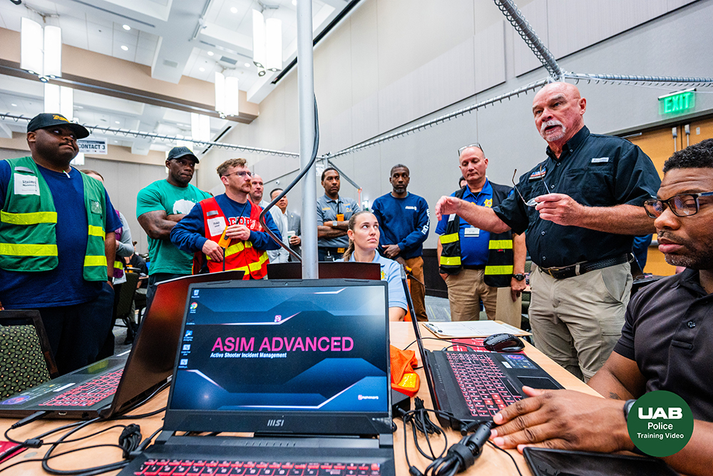 A laptop computer in the foreground reads ASIM Advanced while officers gather in a group around a table