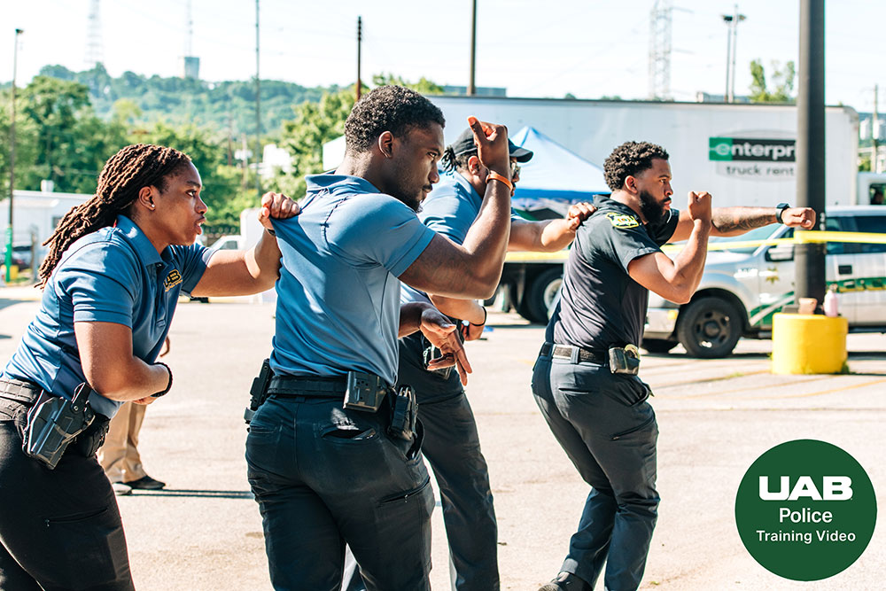 Four UAB police officers walk in pairs with hands pointed outwards during training exercise