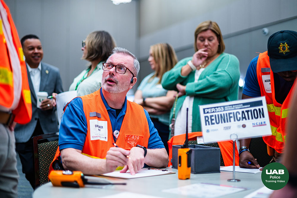 Participants wearing orange vests talk and other participants stand behind in this training exercise