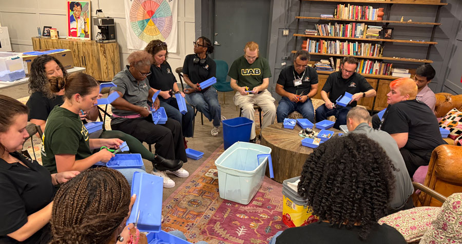 Staff from the UAB Office of Innovative Teaching and Academic Engagement gather in a circle to trim surgical trays at local nonprofit Community on the Rise