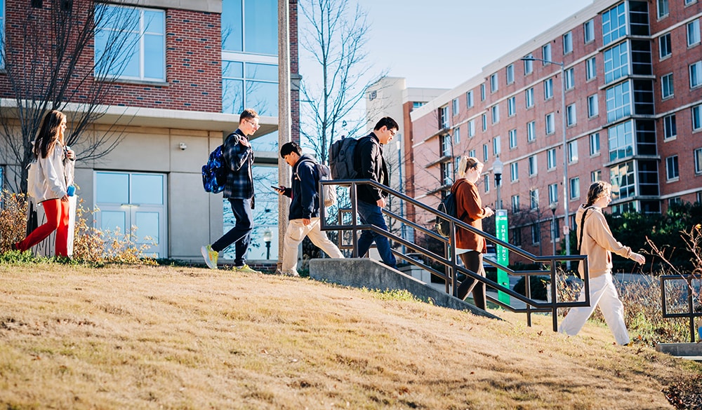 Students, seen in profile, walk down the stairs from Gold Hall to 16th Street South