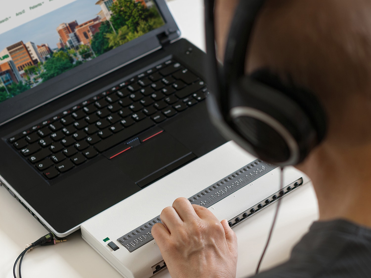 A student using an assistive technology device and wearing headphones browses the UAB website