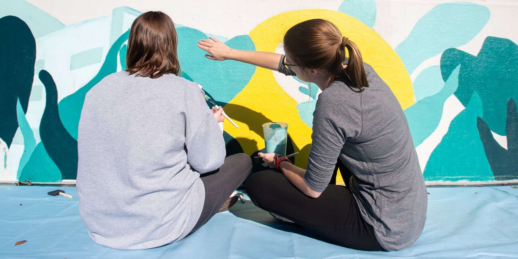 Two female students painting a mural on one of the UAB bridges.