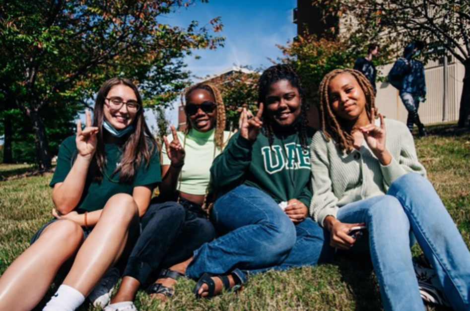 Four students sitting on the UAB campus green. 