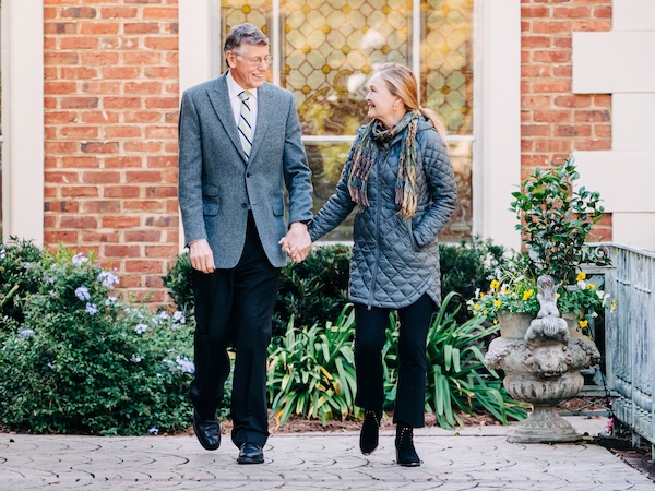 Marnix E. Heersink, M.D., and Mary Heersink walking outside hand-in-hand.