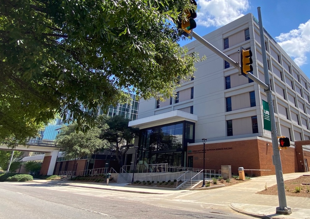 Wide shot of facade of Webb building looking across University Boulevard. This shows the beautiful glass entry way in relation to the entire building and the street.