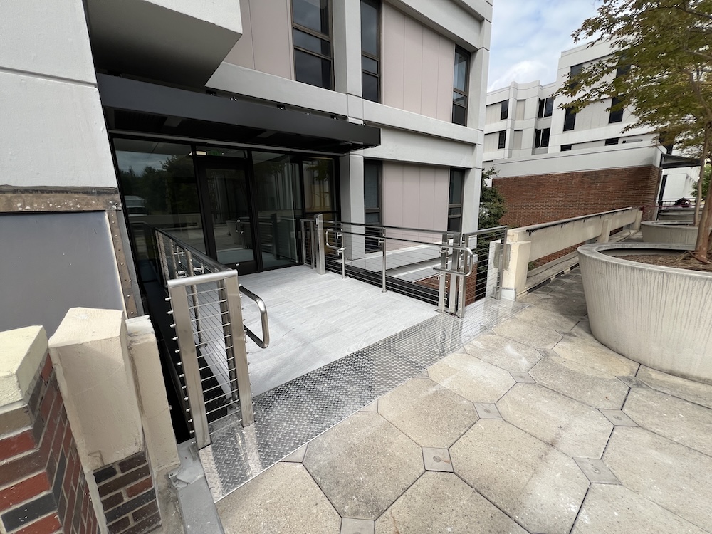 Looking toward the glassed in entrance you see silver railings and a marble entryway that is level.
