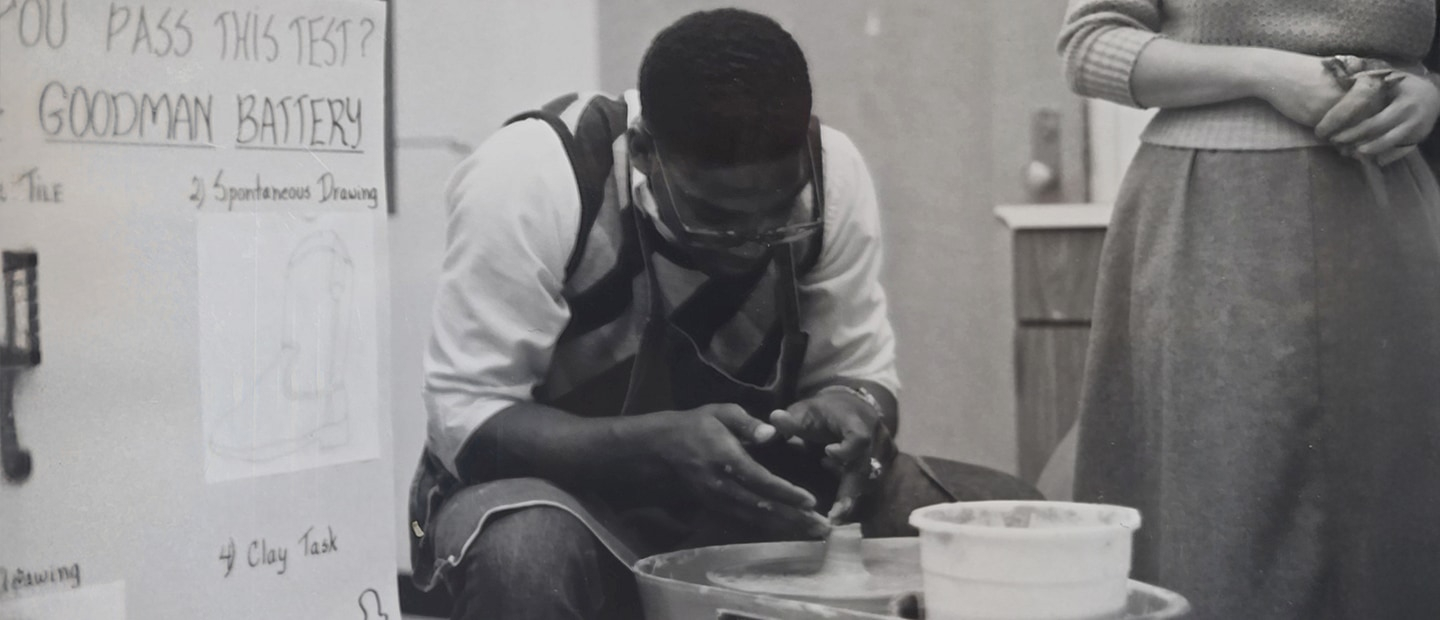 A young Black man in the 1980s working at a pottery wheel.