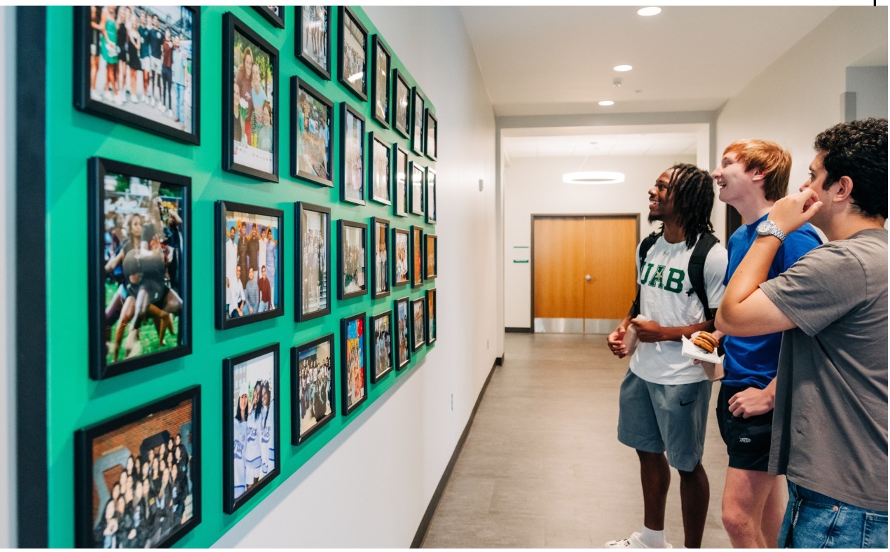 Three students looking at pictures in the SAB during the facility's grand opening.