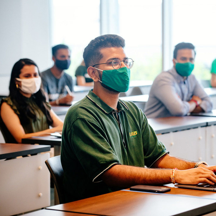 Student wearing mask, seated in Collat School of Business classroom