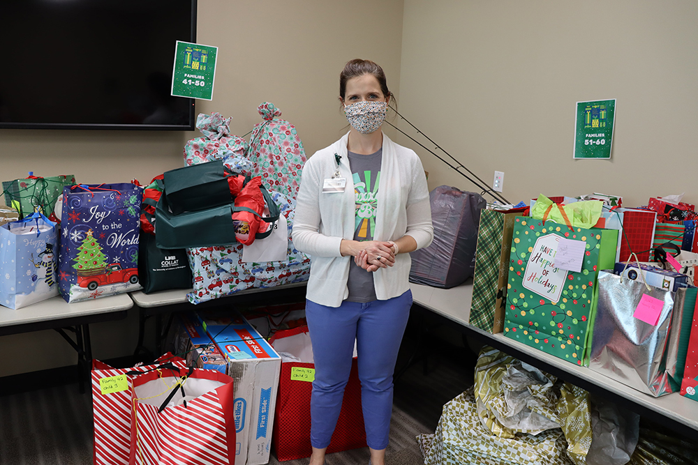 Meredith Kahl, director of Off-Campus Student and Family Engagement, standing amongst a pile of donated presents (2021)