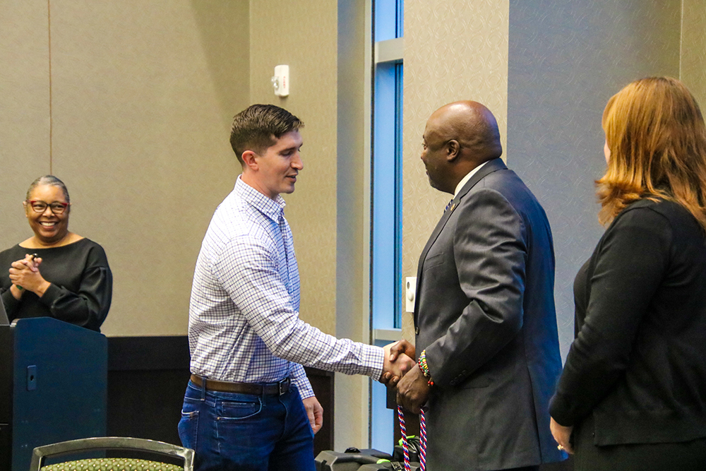 Walter C. Stewart, Veteran Recruitment and Student Services director, shakes the hand of a graduating veteran student during Coins and Cords ceremony.