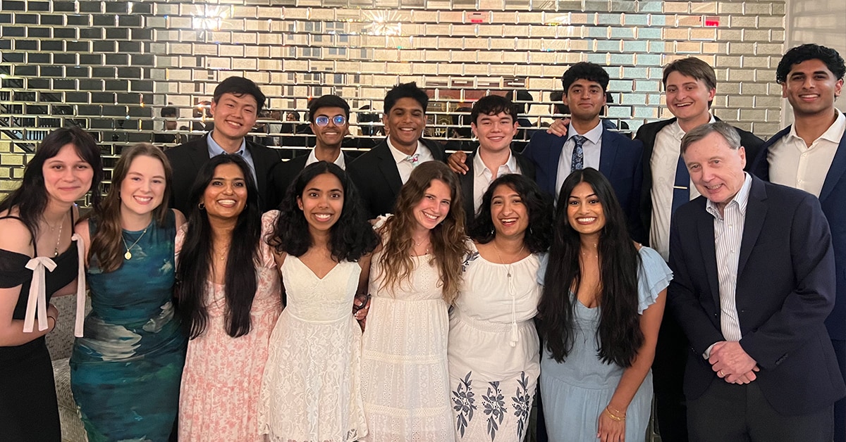 EMSAP students pose with Dr. Pence in front of a silver brick wall.