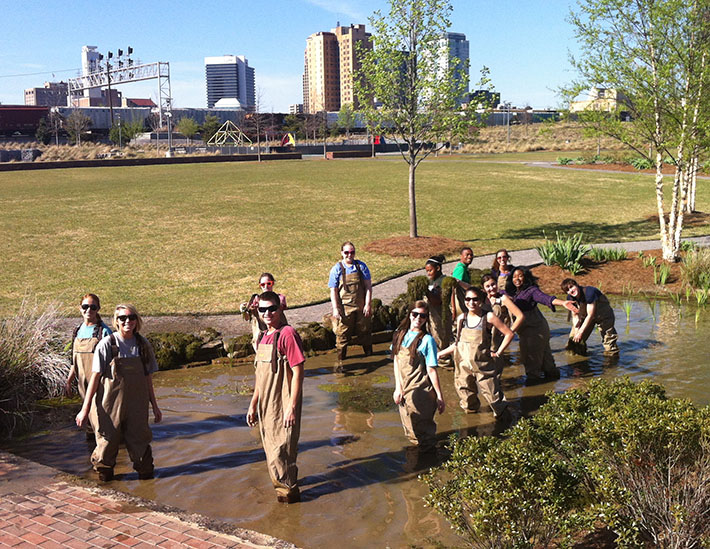 UAB students cleaning algae from Railroad Park streambeds
