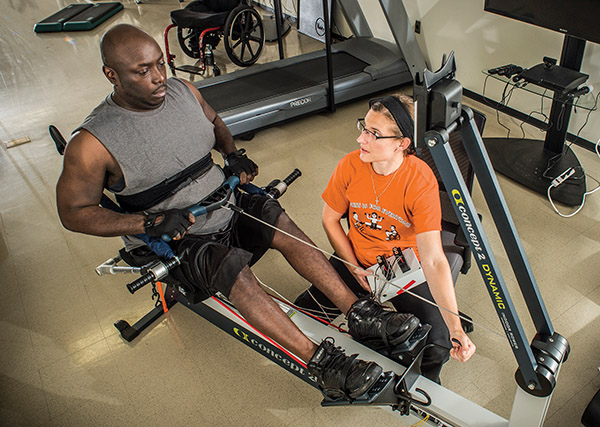 Photo of athlete and trainer on adapted rowing machine