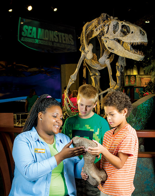 Photo of Kristen Bates showing model of dinosaur bone to campers