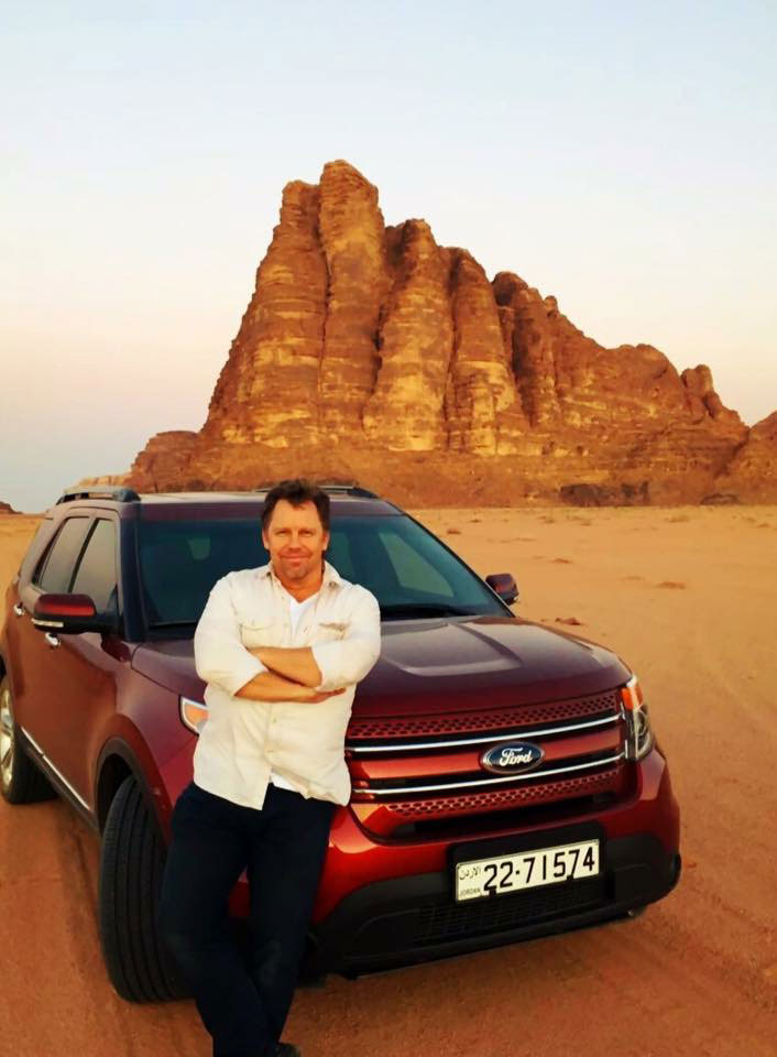 Photo of Trevor Hale with a Ford SUV in the desert