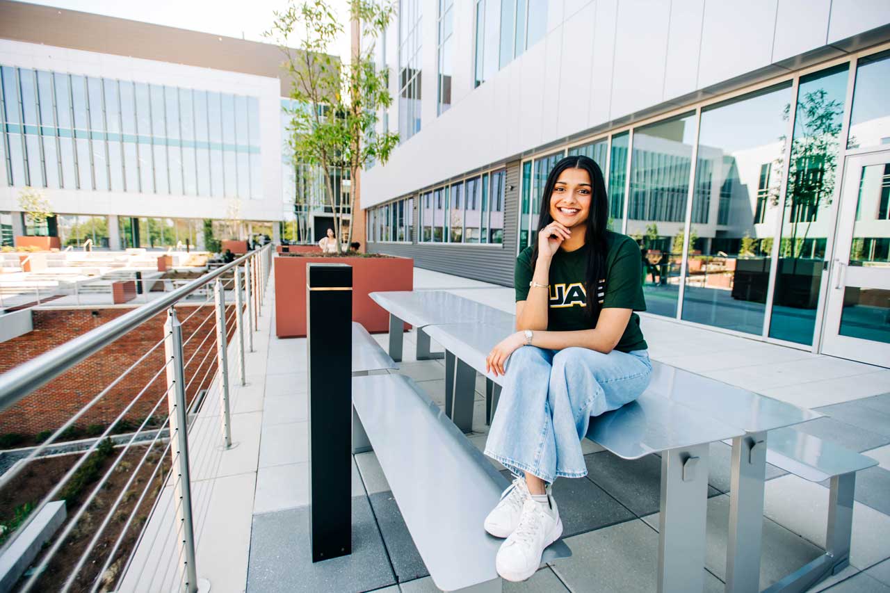 A student sits on a bench outside of the Science and Engineering Complex.