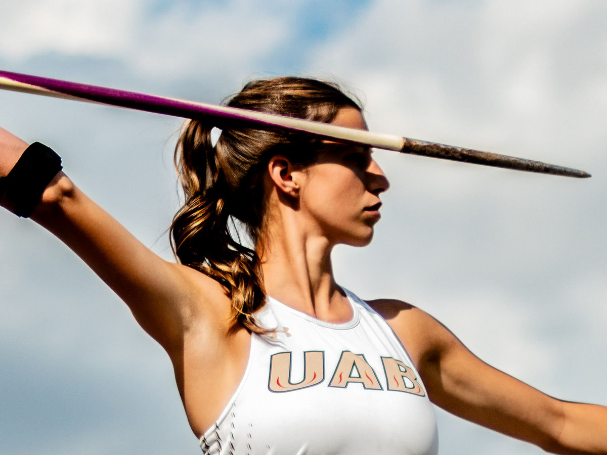 Close-up of a female student-athlete is throwing a javelin at the UAB Track and Field Facility.