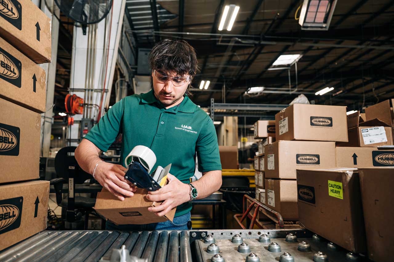 Hollingsworth tapes a box in a warehouse.