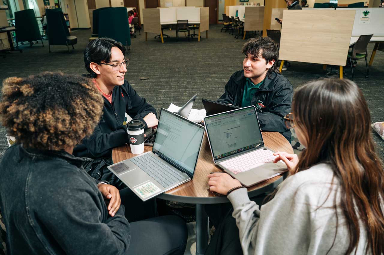 Hollingsworth meets with friends around a table with laptops.