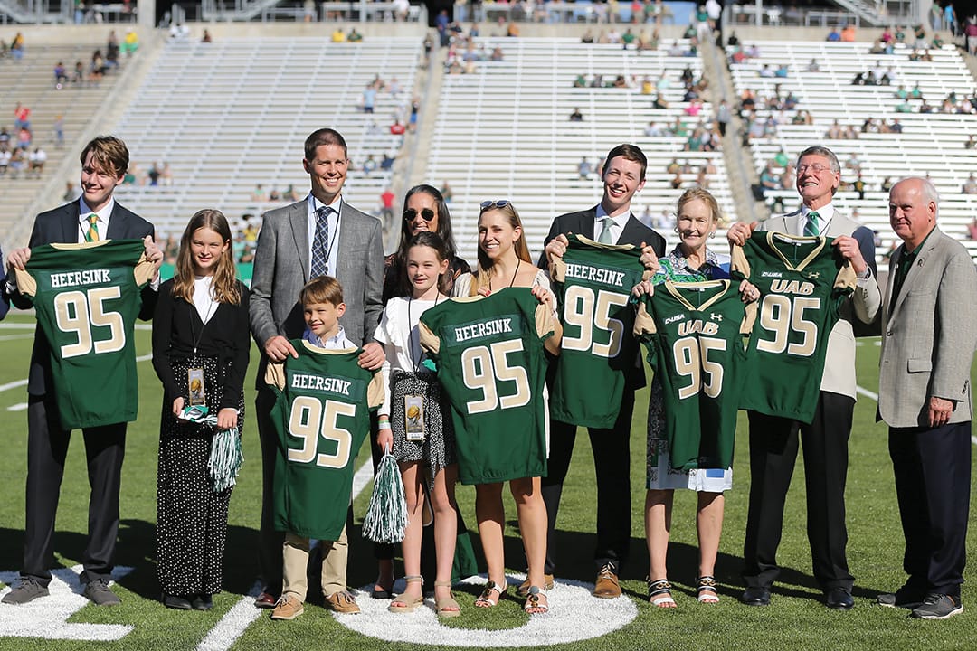 Photo: President Ray Watts presents the Heersink family with commermorative jerseys at a UAB Football Game