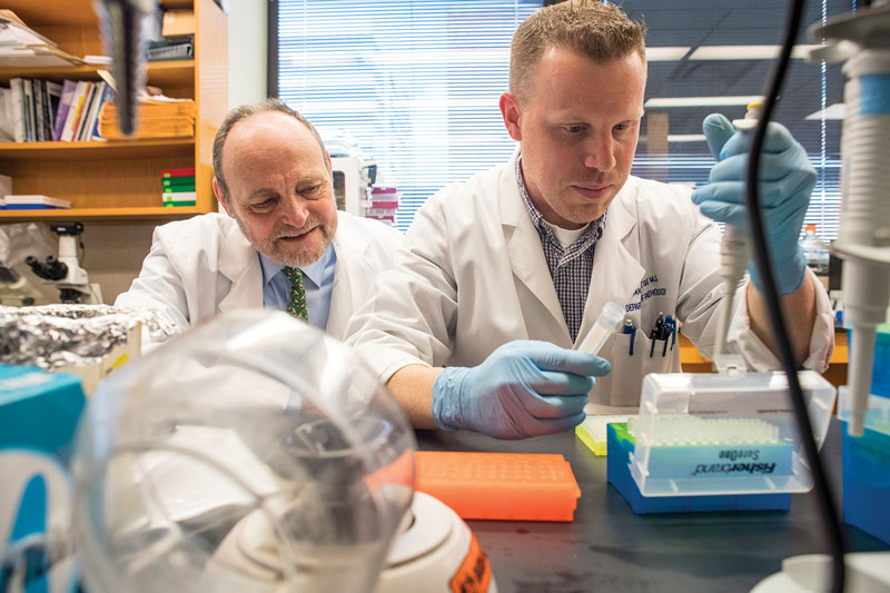 Michael Birrer working in research lab with another researcher.