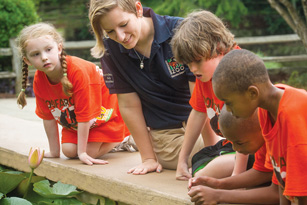 UABTeach student teaching three elementary students about water habitats at the Birmingham Botanical Gardens.
